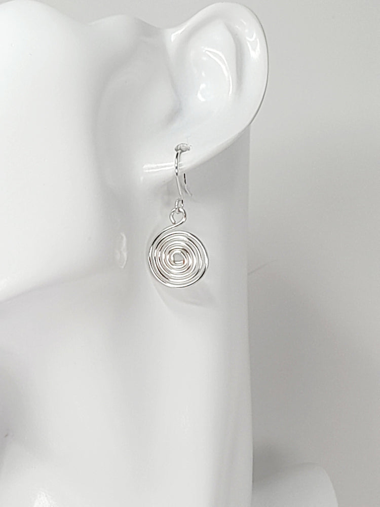 Silver spiral earring worn on white mannequin.