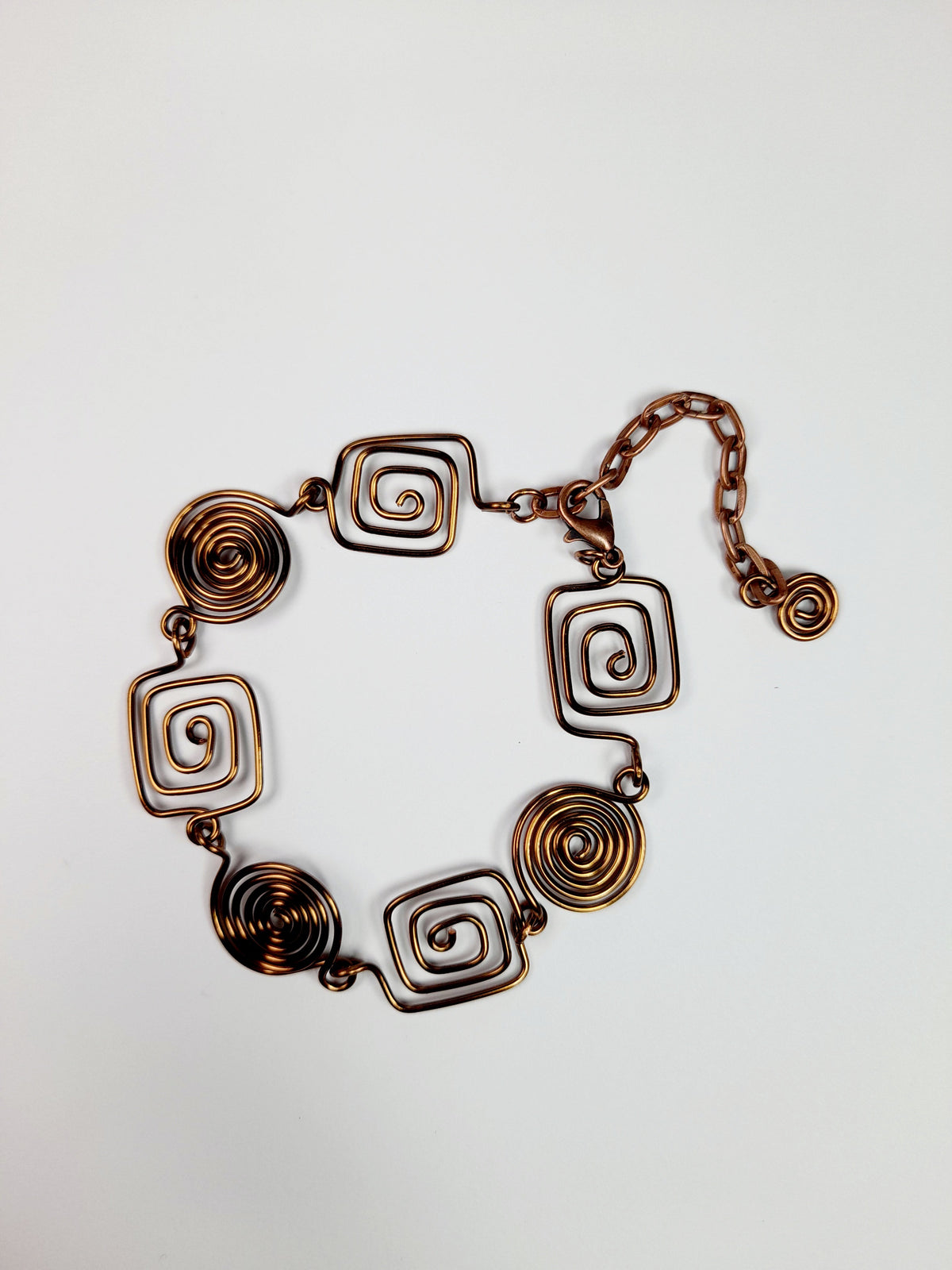 Bronze spiral bracelet made from four square and three round spirals, finished with a bronze plated lobster clasp and extension chain decorated with a tiny round spiral.