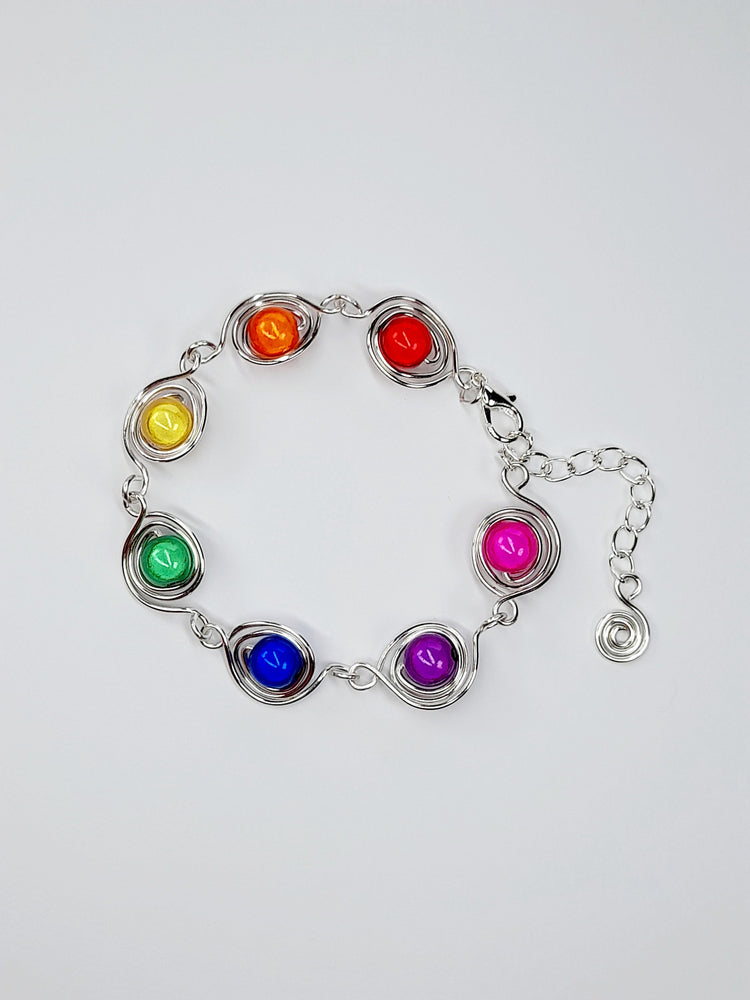 Bracelet with beads in each colour of the rainbow, each bead is surrounded with a silver swirl and the bracelet is finished with a silver lobster clasp and a silver extension chain