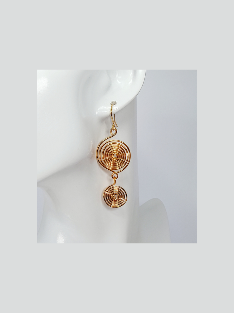 Gold spiral earrings with a large and small spiral dangling from one another on a gold plated handmade ear wire hook.