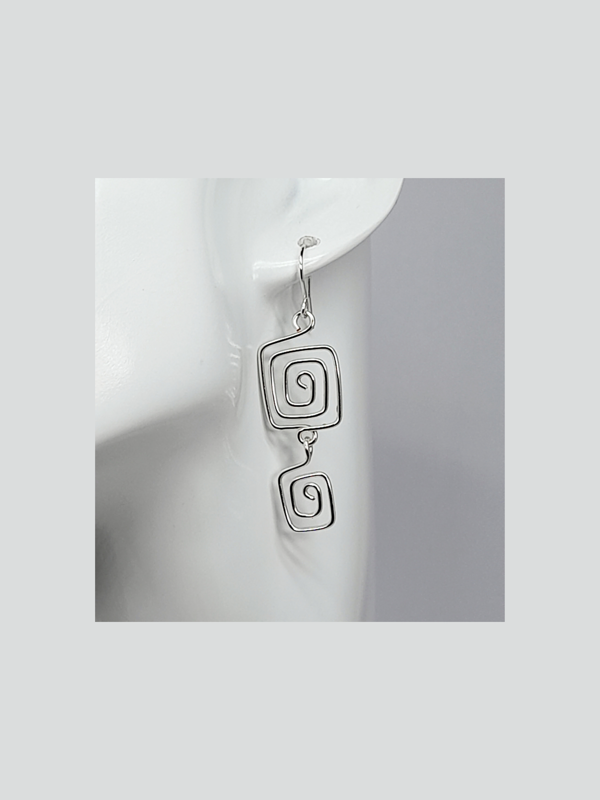 Silver plated drop spiral earrings made with two square spirals hanging on a silver plated ear wire hook.