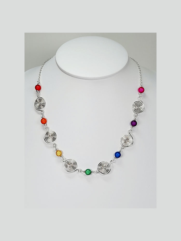 Handmade necklace with alternating rainbow coloured miracle beads alternating with handmade silver spirals, finished with silver plated chain and a silver plated lobster clasp.
