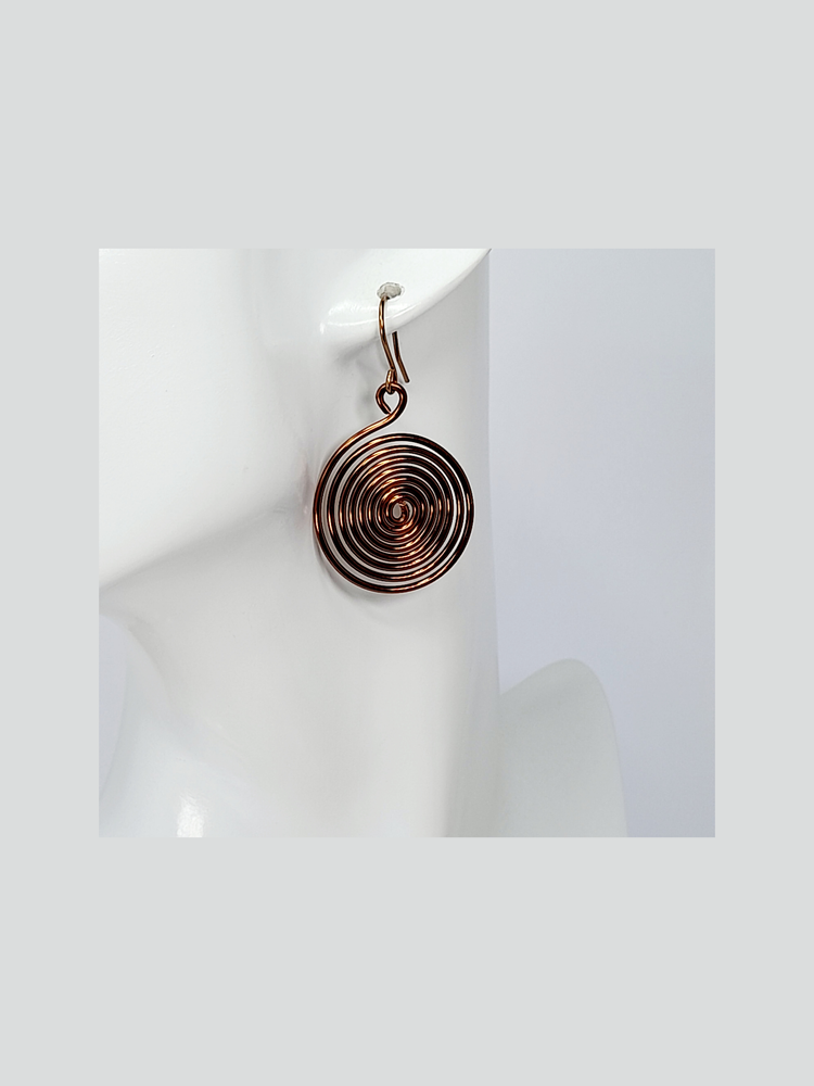 An earring made from a large handmade bronze spiral hanging from a bronze plated ear wire hook.