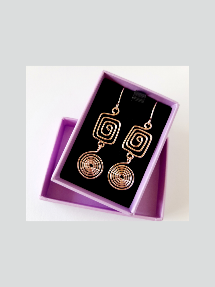  handmade pair of rose gold spiral earrings displayed in a purple gift box with a black lining