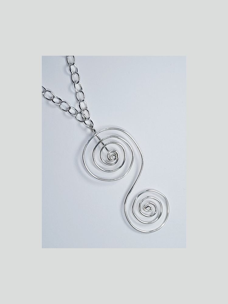 An "S" shaped silver spiral pendant with silver chain shown on a white background.