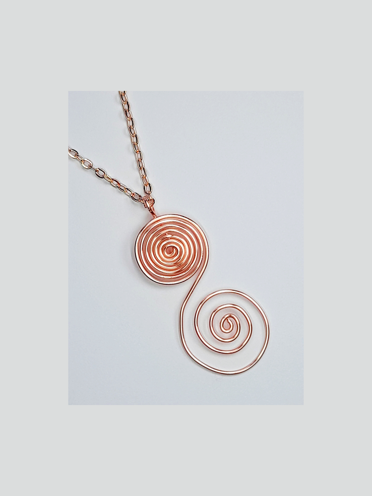 Rose gold "s" shaped pendant and rose gold chain shown on a white background.