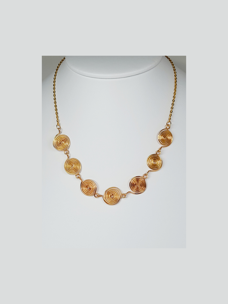 Gold spiral and chain necklace shown on a white background.