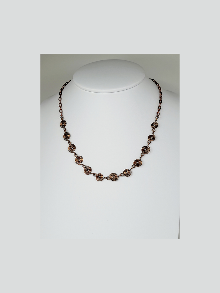 Bronze spiral and chain necklace on a white background.