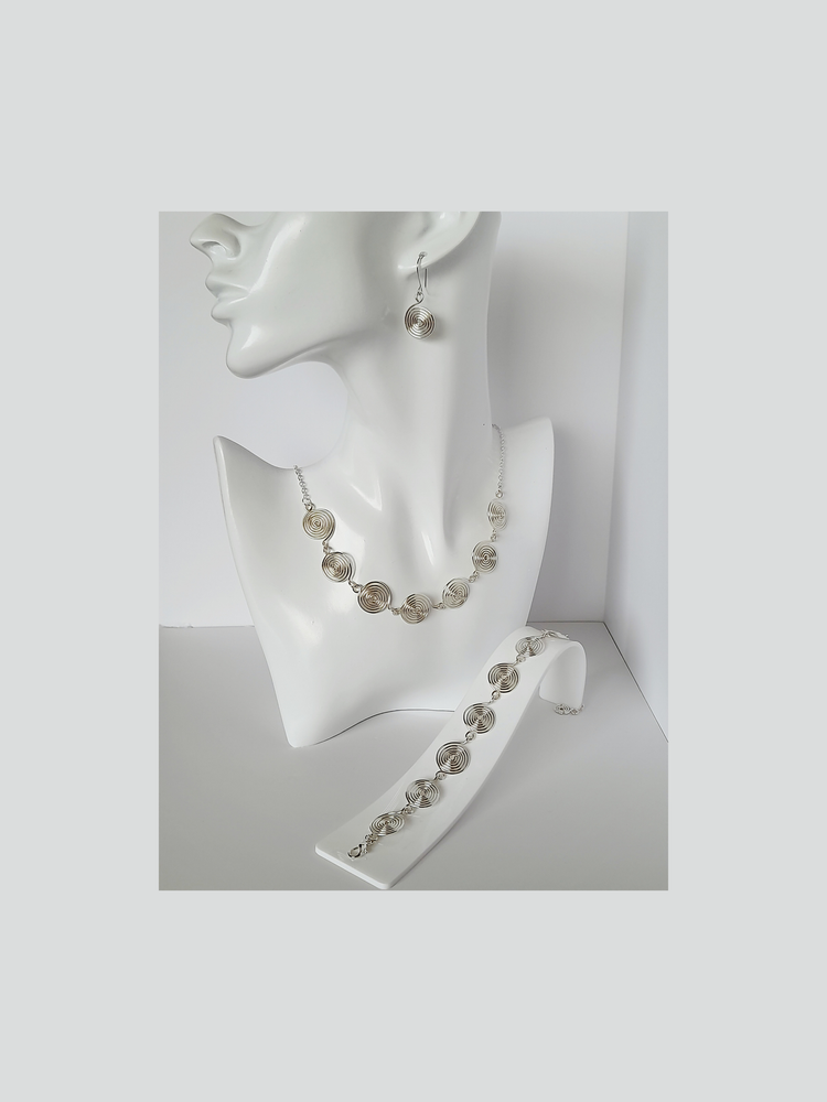 Handmade silver spiral set made up of drop earrings, necklace and bracelet shown worn on a white mannequin