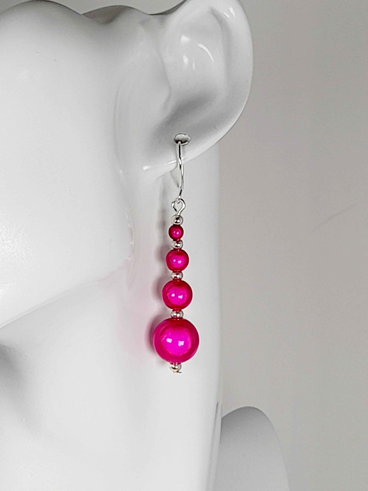Hot pink miracle bead drop earrings on a white mannequin head