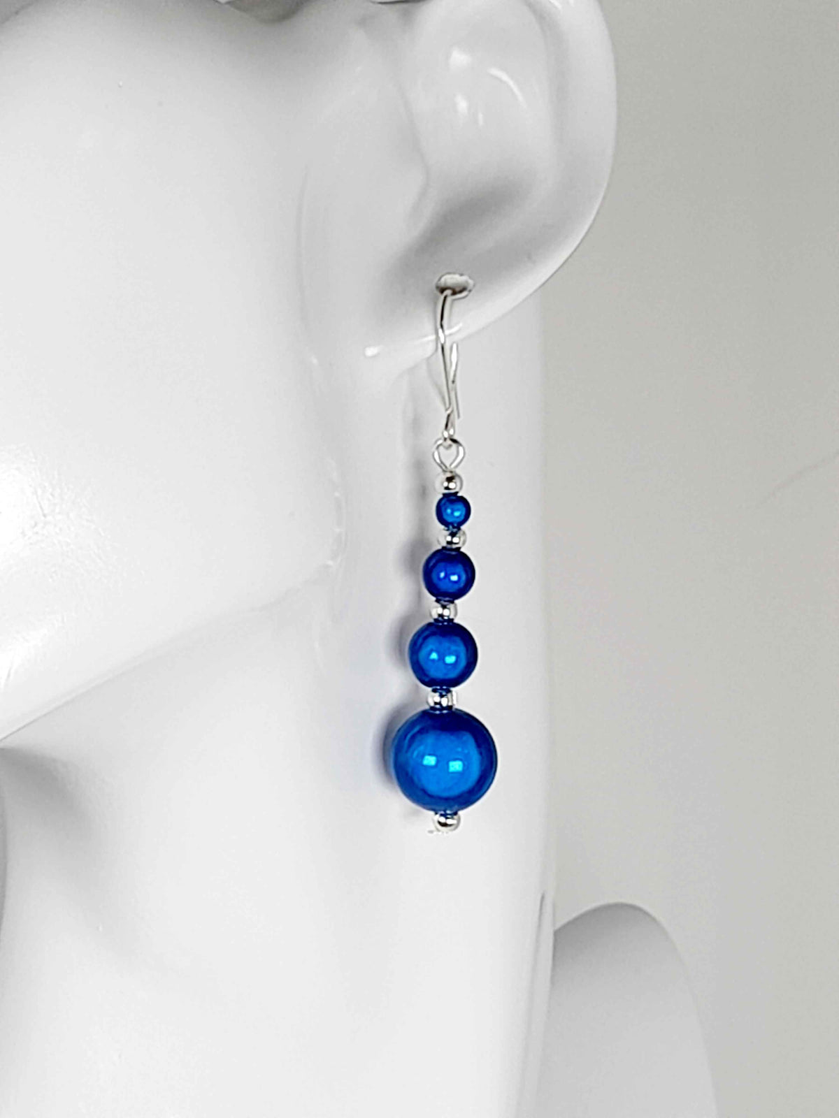 Bright Blue Miracle Bead Earrings worn On A white Mannequin Head