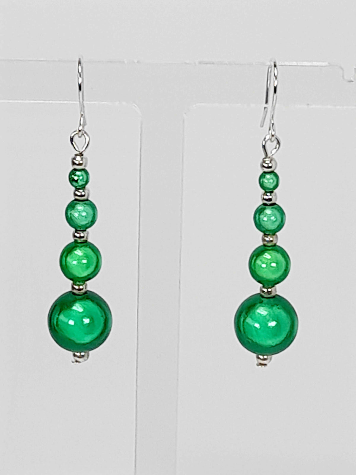 Bright green miracle bead earrings on white background.