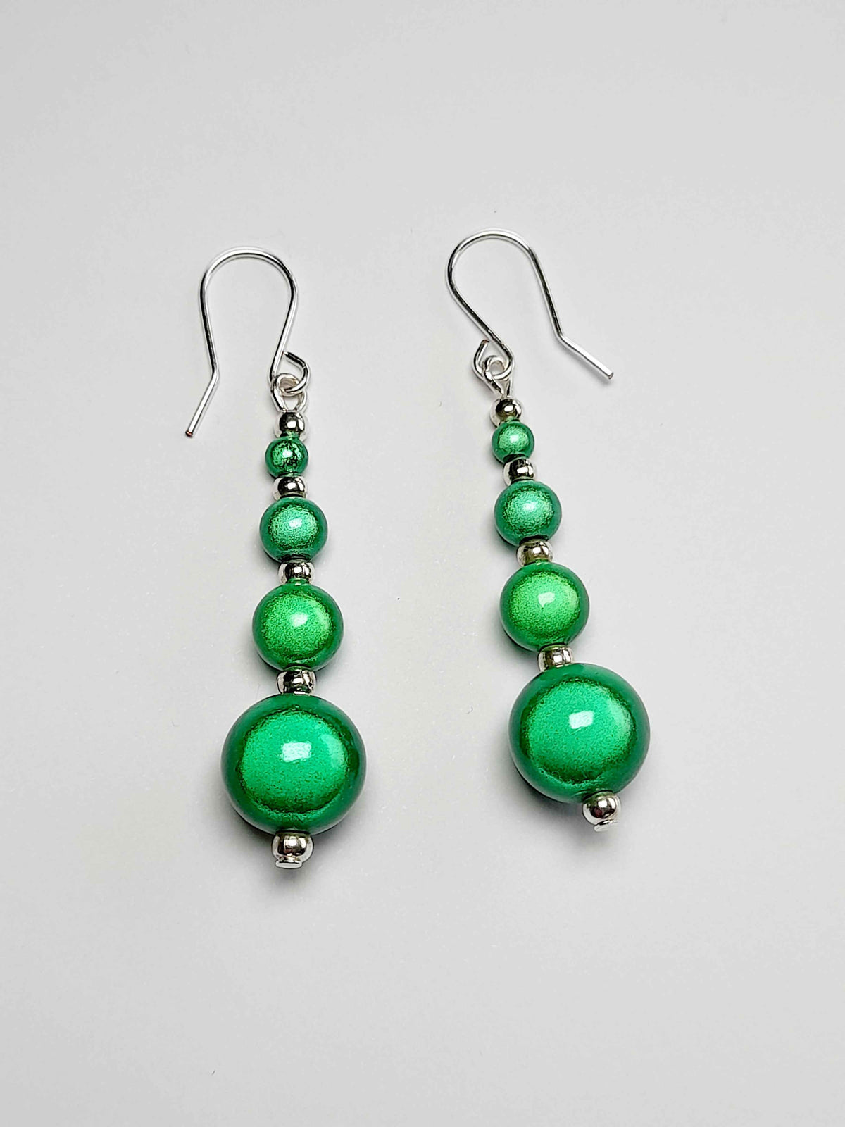 Bright green miracle bead earrings on white background.