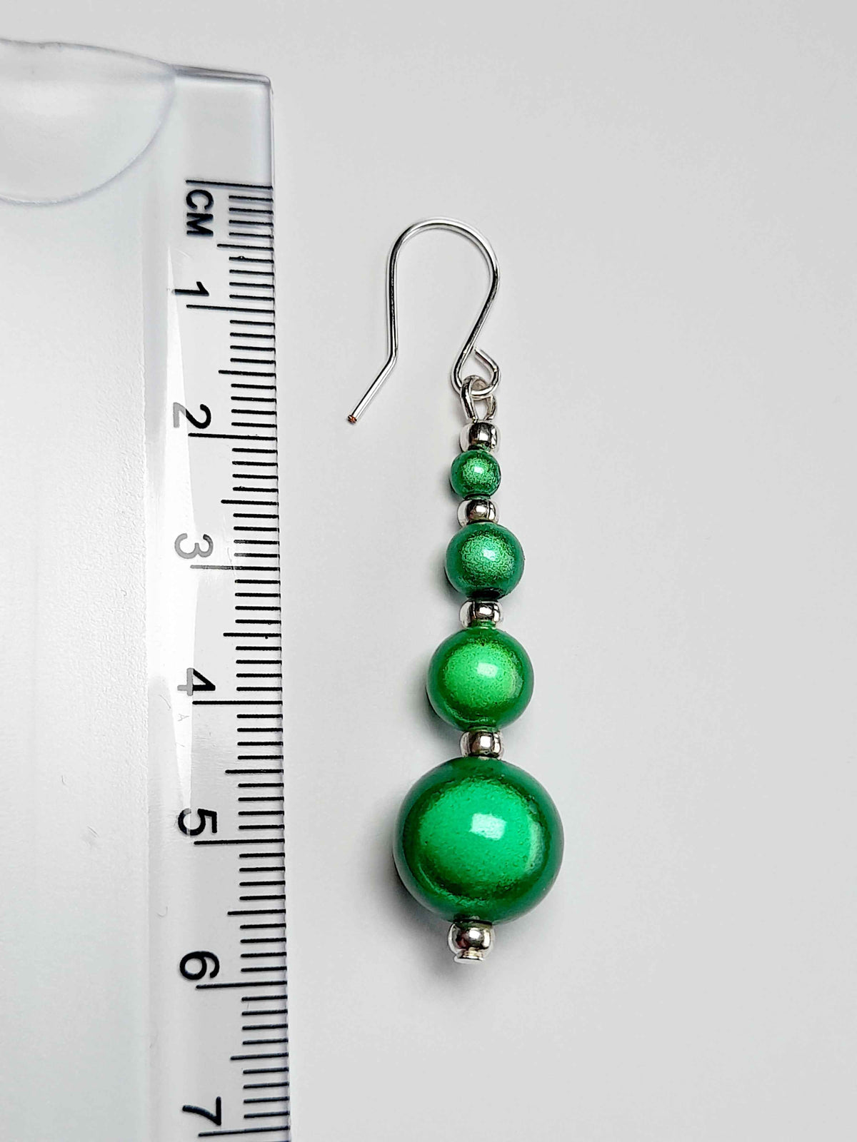 Bright green miracle bead earrings with ruler showing 6cm drop.