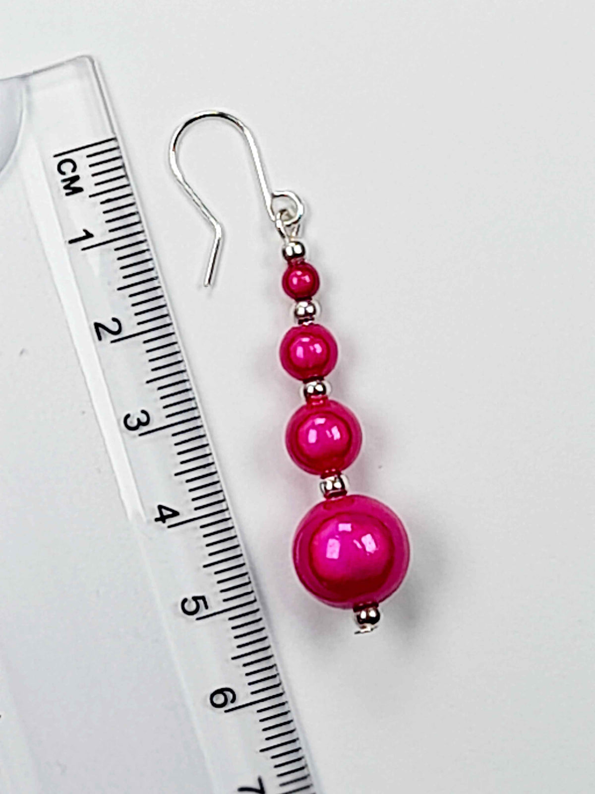 Hot Pink Luminescent Bead Earring on a white background with ruler showing 6cm drop.