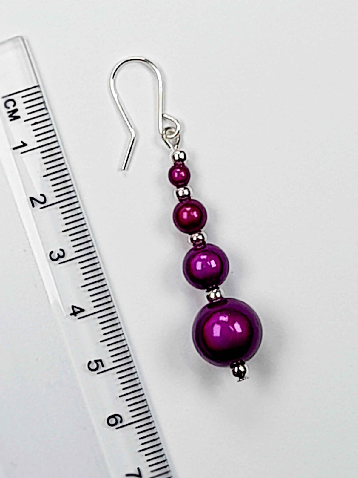 Bright purple miracle bead earrings with ruler showing 6cm drop.