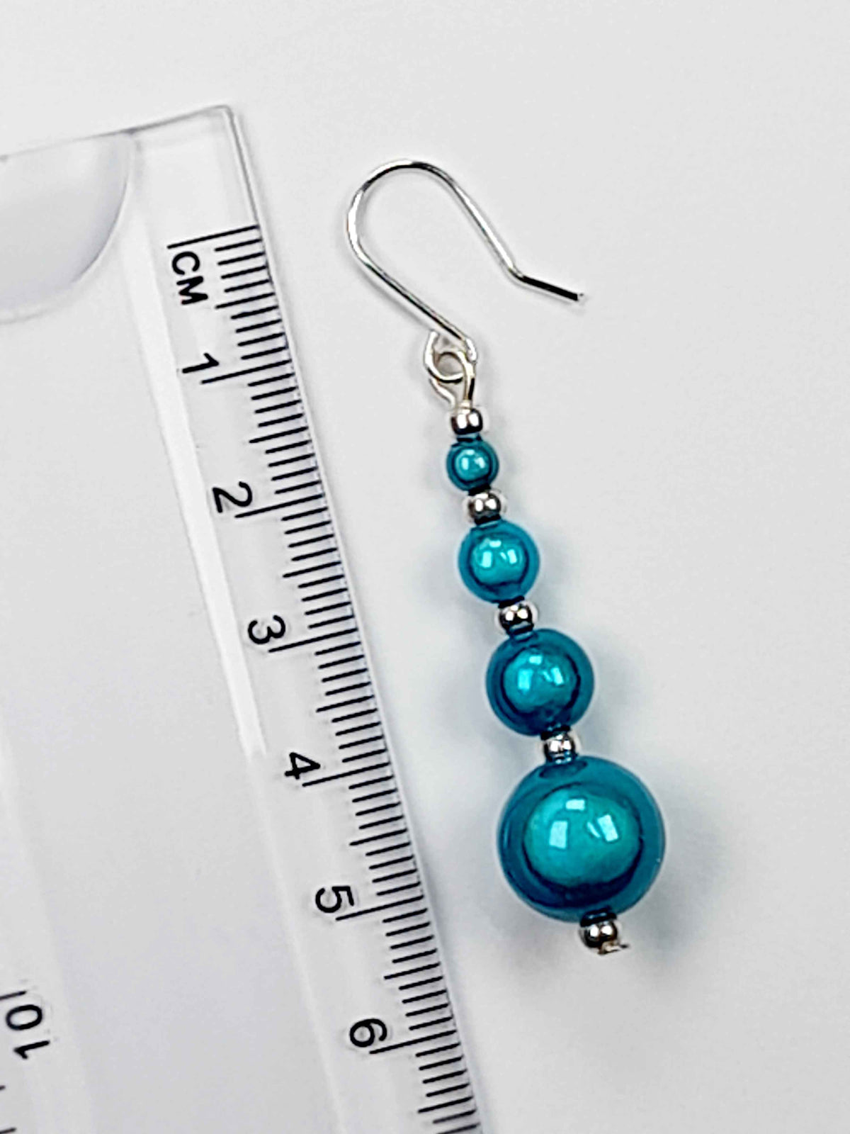 Turquoise blue miracle bead drop earrings with a ruler showing a 6cm drop