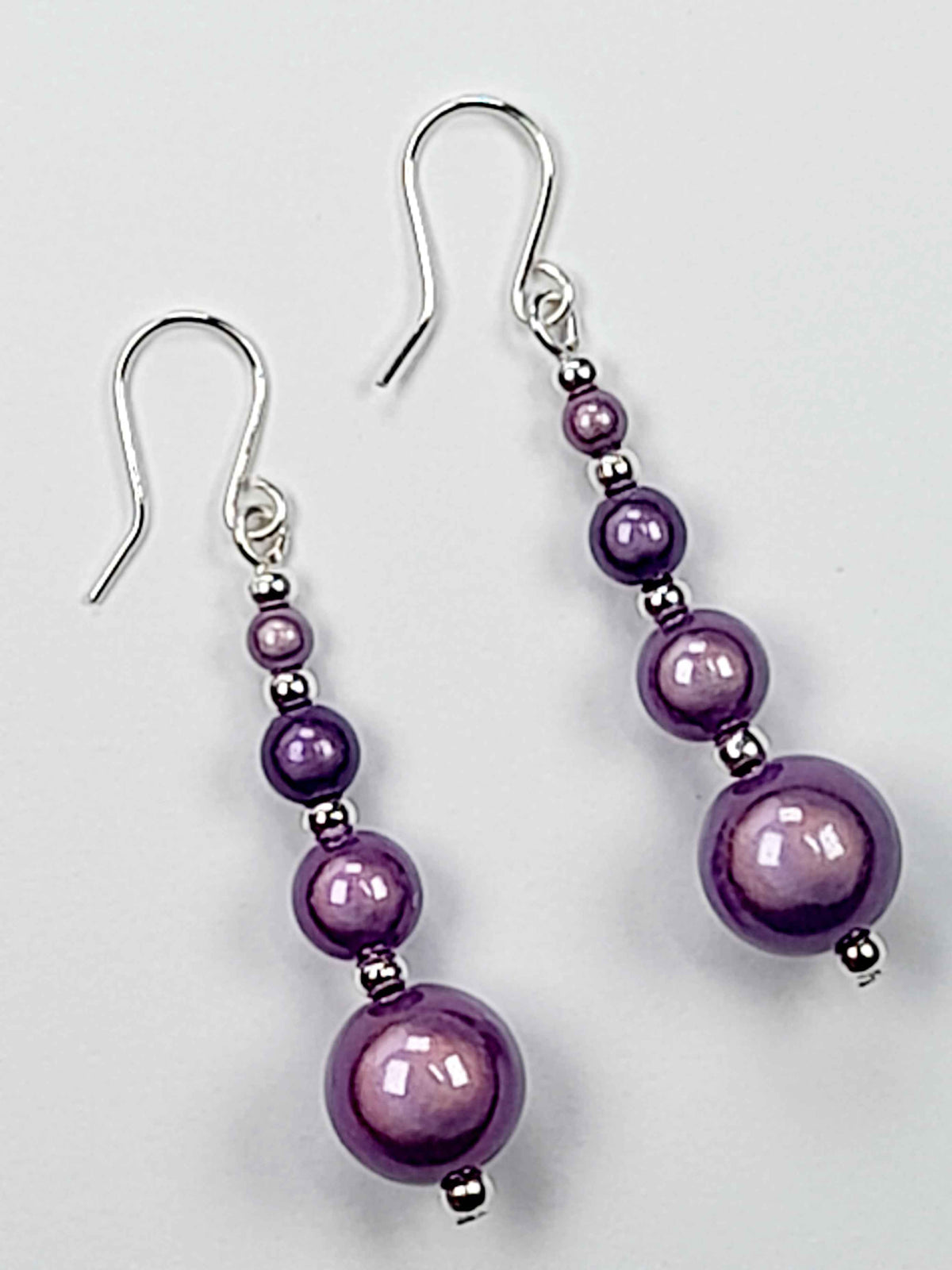 Lilac miracle bead earrings with silver ear hooks displayed on a white background.