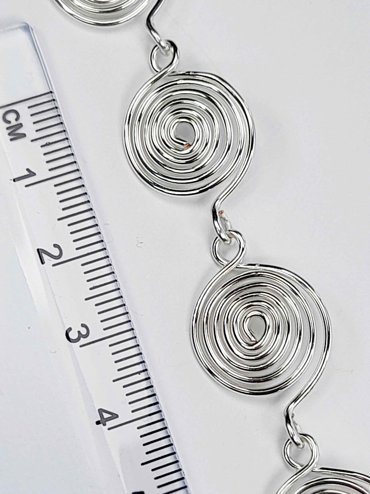 Silver spiral bracelet detail – close-up of handcrafted wire swirls with ruler