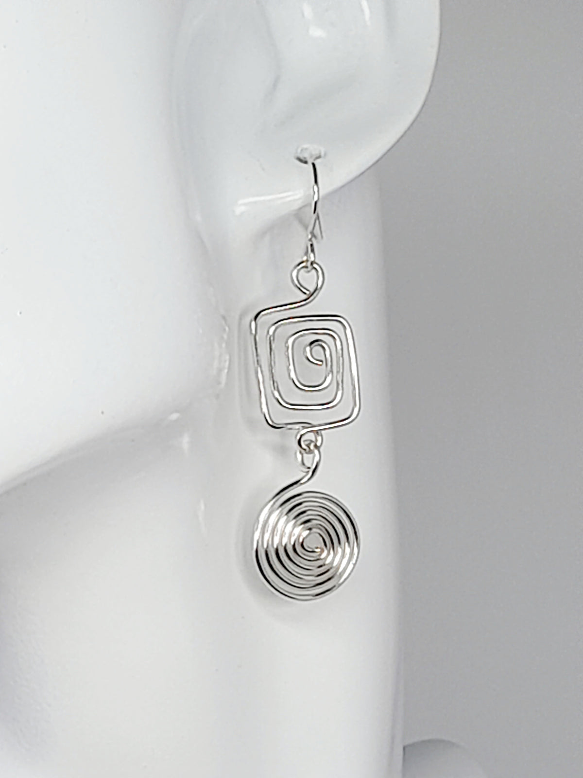 Handmade silver geometric double spiral drop earrings showing square top spiral and round dangling bottom spiral